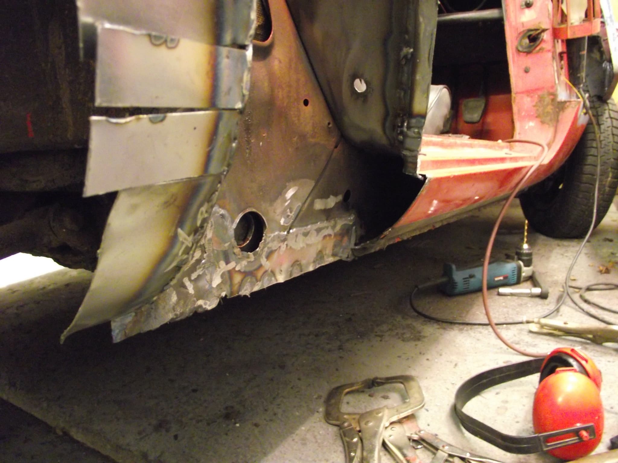 New steel welded into the lower body of a red Spitfire at the front of the door opening.
