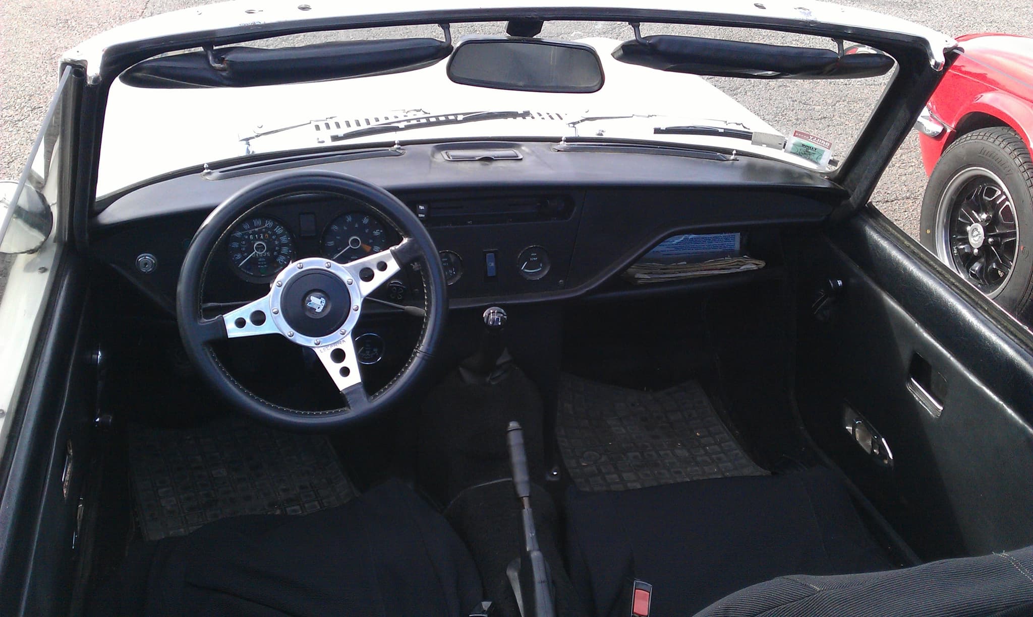 A Spitfire Mk IV cockpit from above, with a black fascia, instruments ahead of the driver and black seats. Opens a larger view