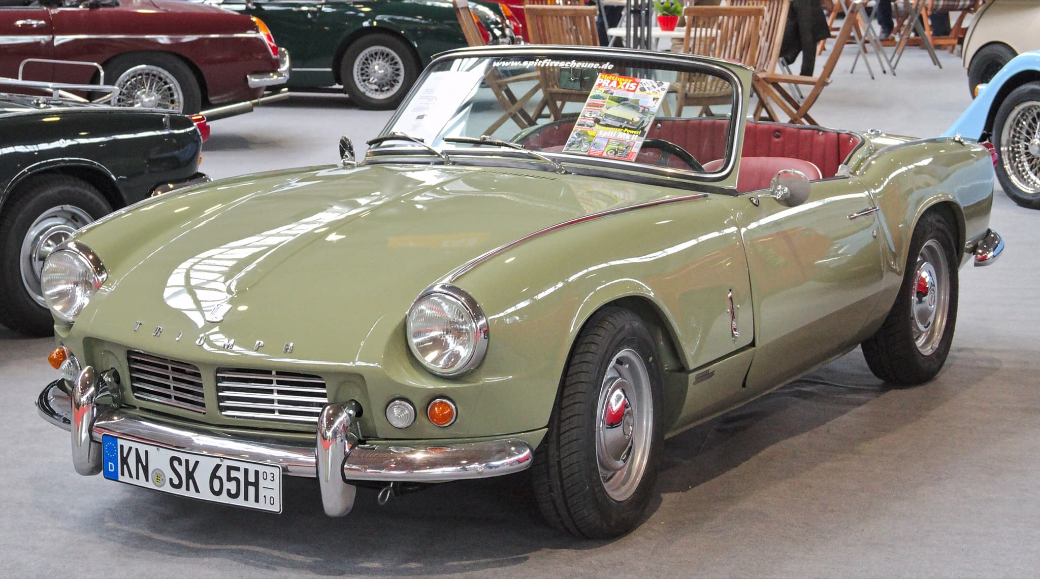 A pale sage-green Spitfire 4 Mk II with a red interior on a show stand indoors. Opens a larger view