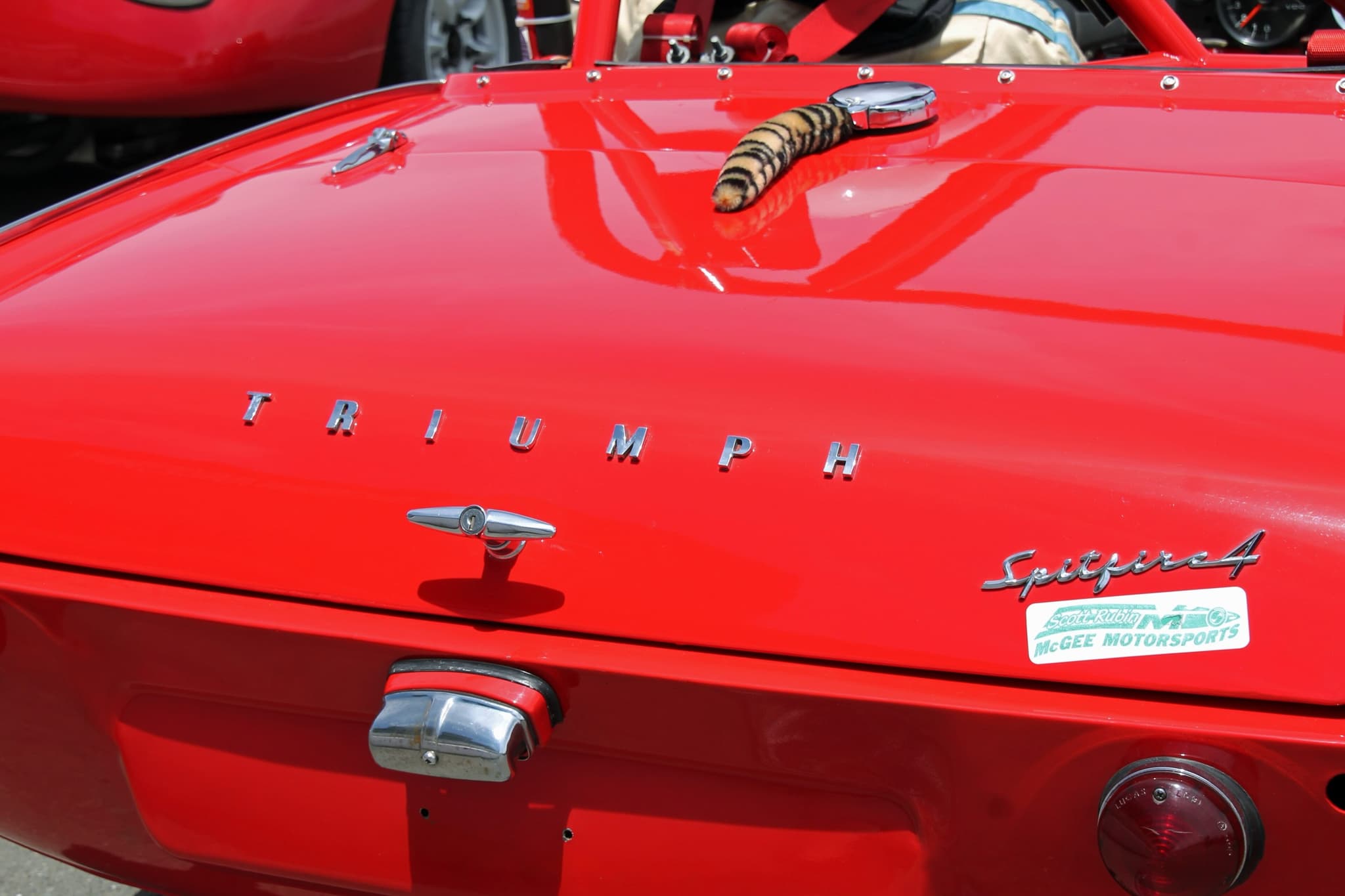 Close-up of a red Spitfire 4 boot lid with chrome TRIUMPH letters, a T-handle and 'Spitfire 4' script.