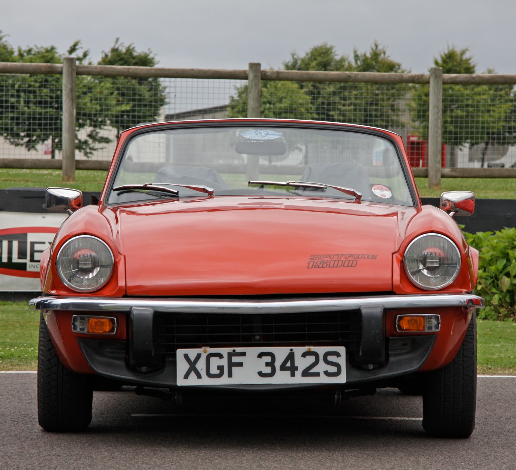 A red Spitfire 1500 with the hood down, square on from the front, its decal on the bonnet.