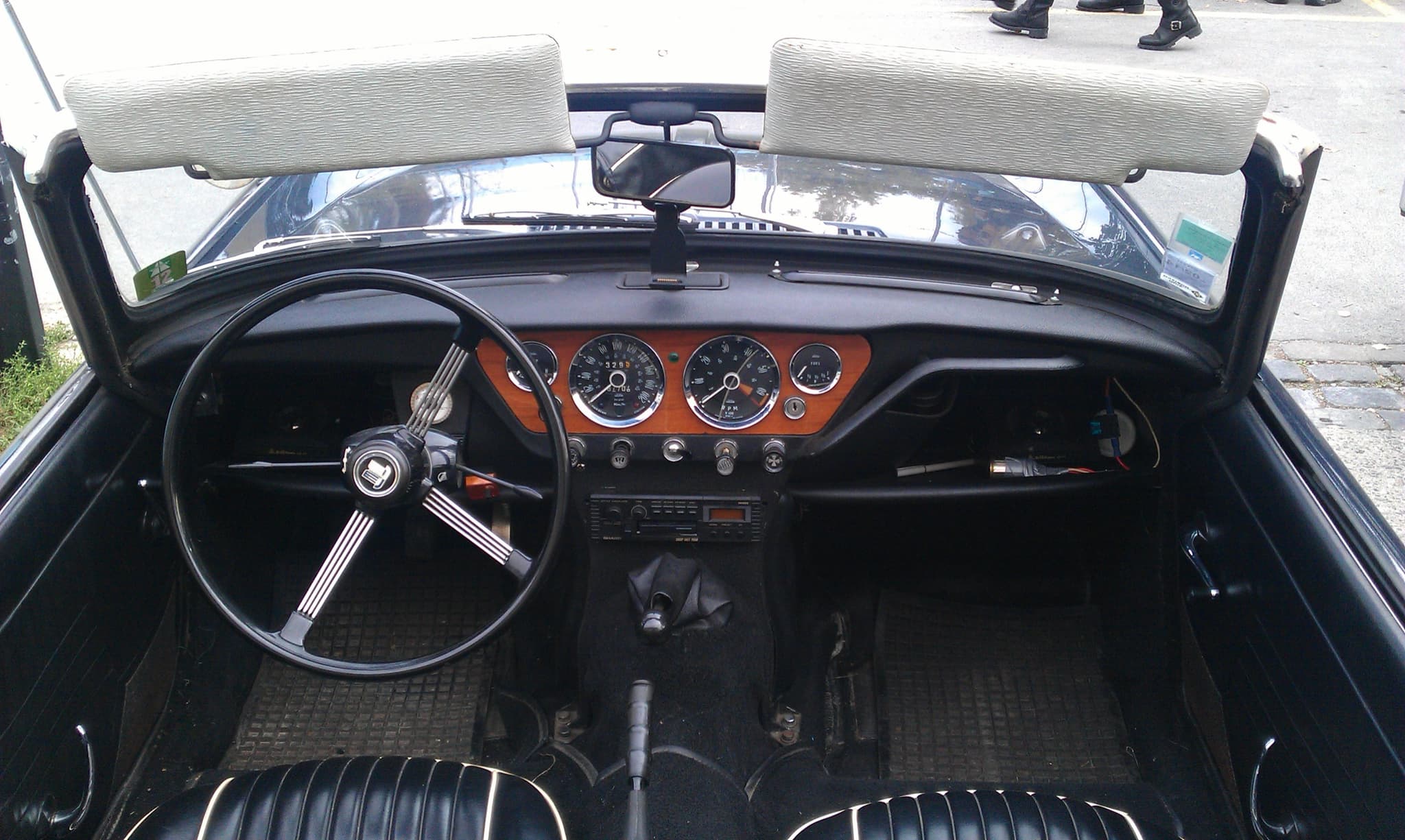 A Spitfire Mk III cockpit from behind the seats, with a wood centre instrument panel and black three-spoke wheel. Opens a larger view
