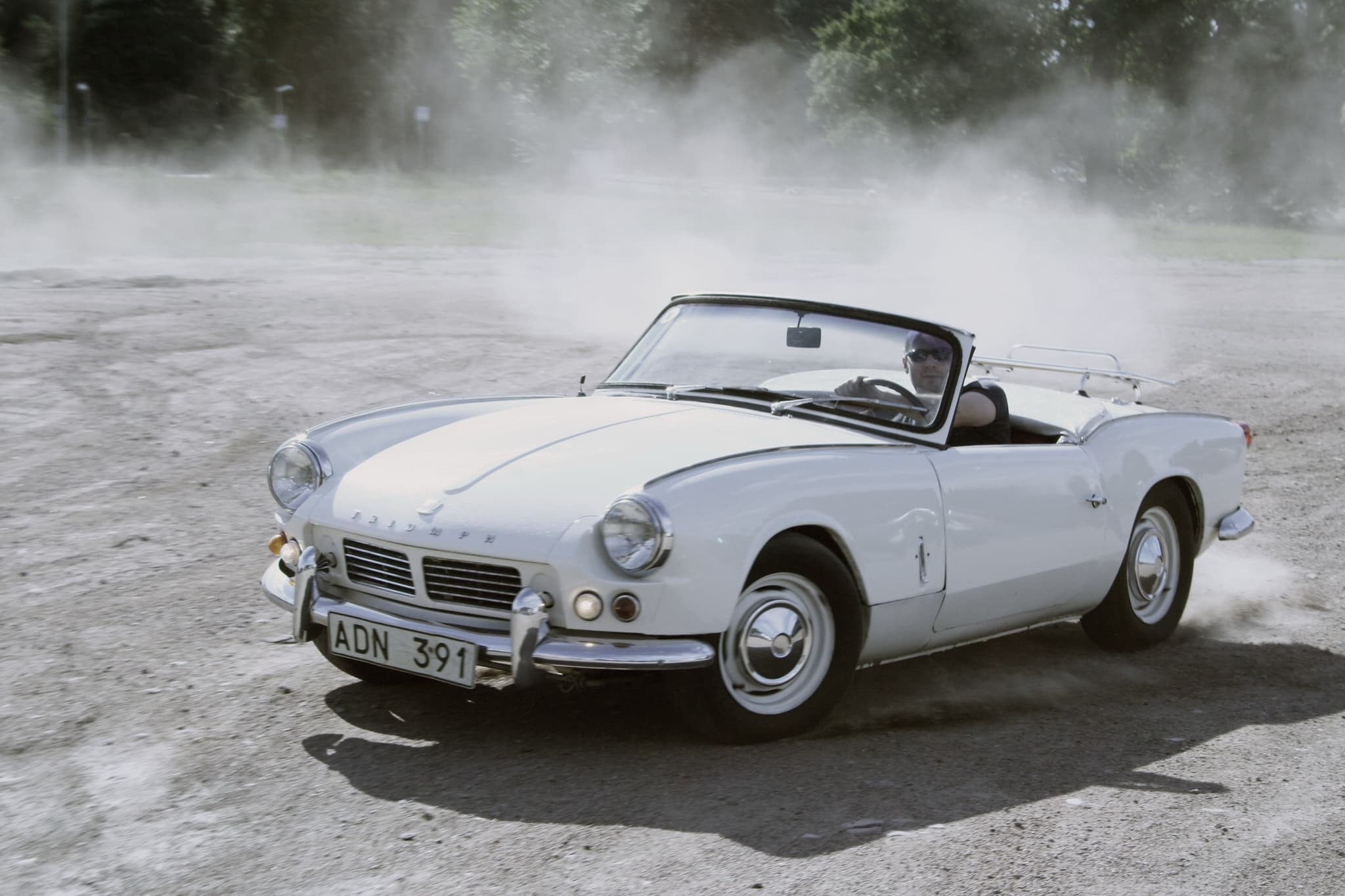 A white Spitfire 4 Mk II sliding across loose gravel, throwing up a cloud of dust. Opens a larger view