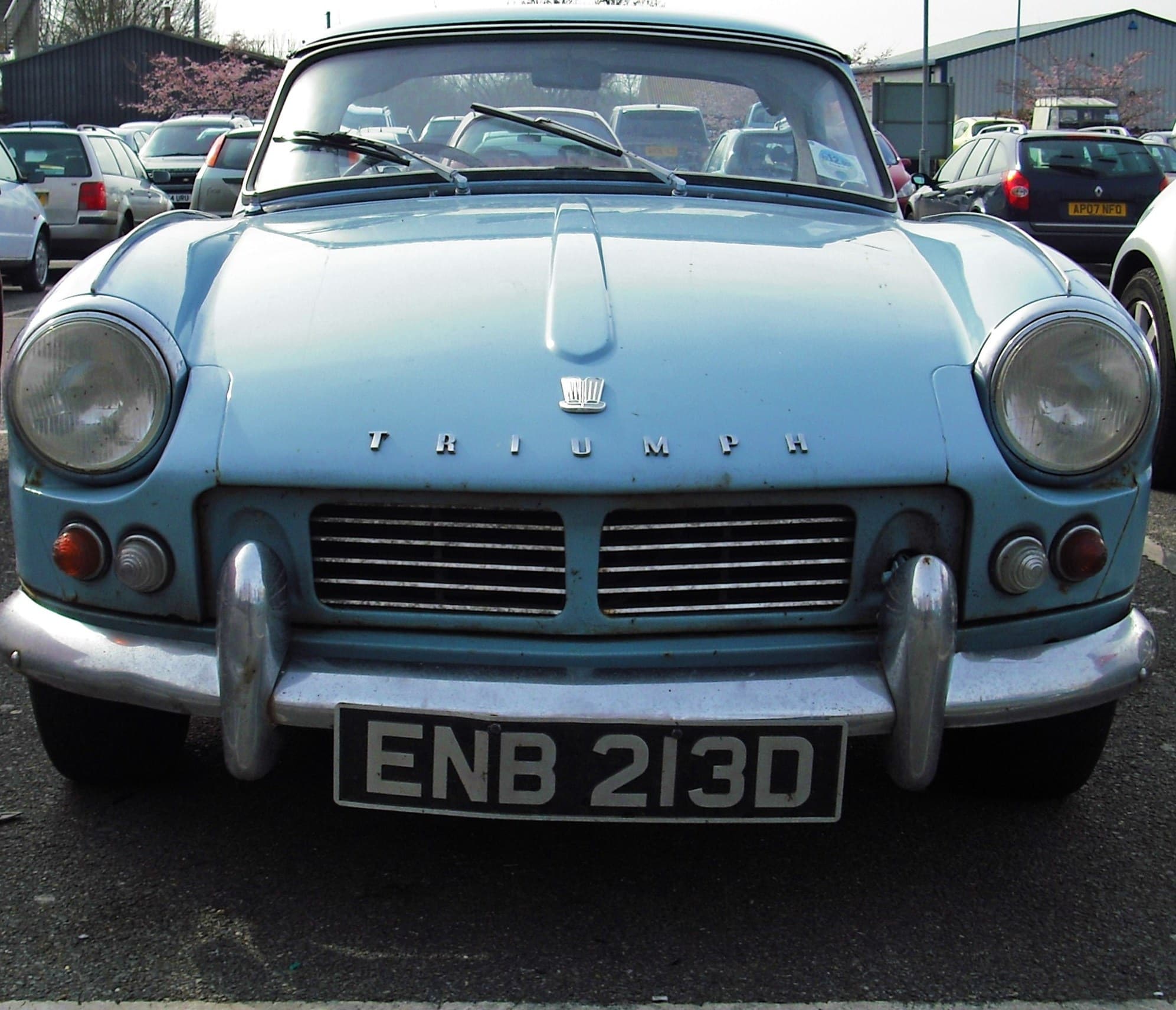 A pale blue Spitfire 4 Mk II with a hardtop, square on from the front, showing its horizontal-bar grille.