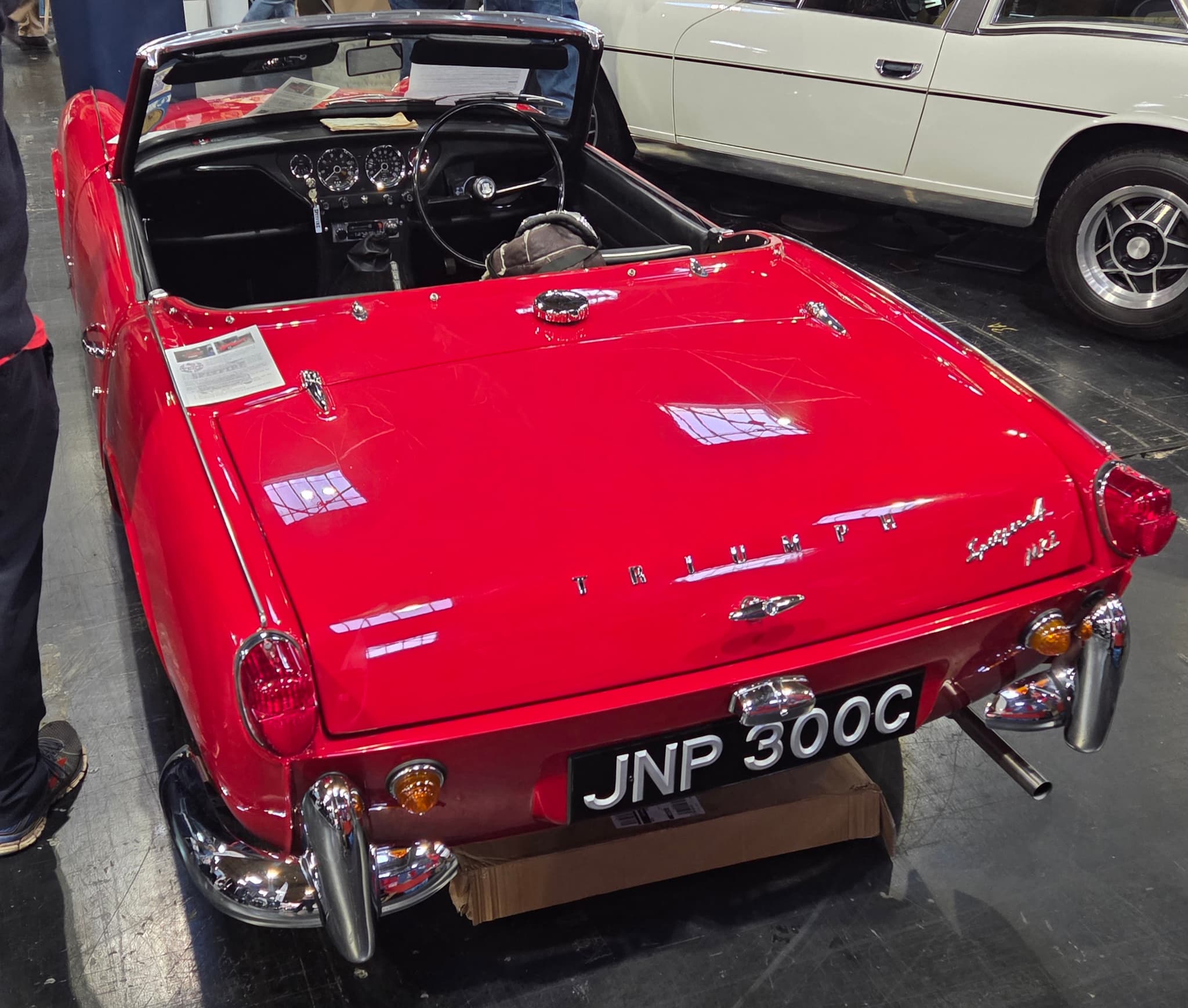 The round tail of a red Spitfire 4 Mk II with its hood down, in a show hall. Opens a larger view