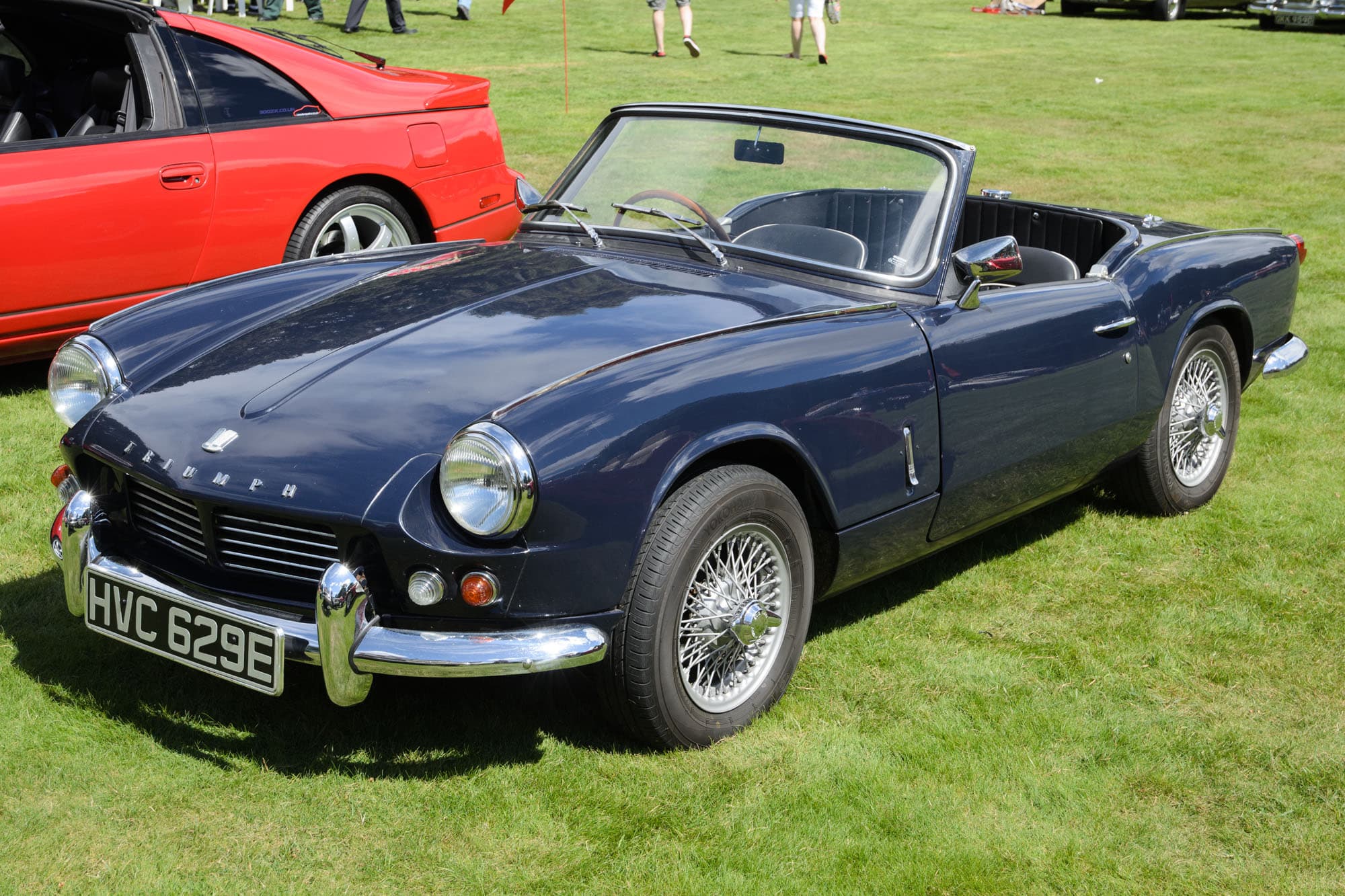 A dark blue Spitfire 4 Mk II with its hood folded and wire wheels on a sunny show lawn. Opens a larger view